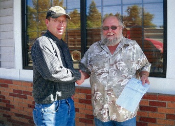 IAM Local Lodge 509 member Corey Martin, right, receives disaster relief check from Local Chairman Gary Whitmer. Martin, of Minot, ND, suffered extensive loss from the record-setting flooding earlier this summer.